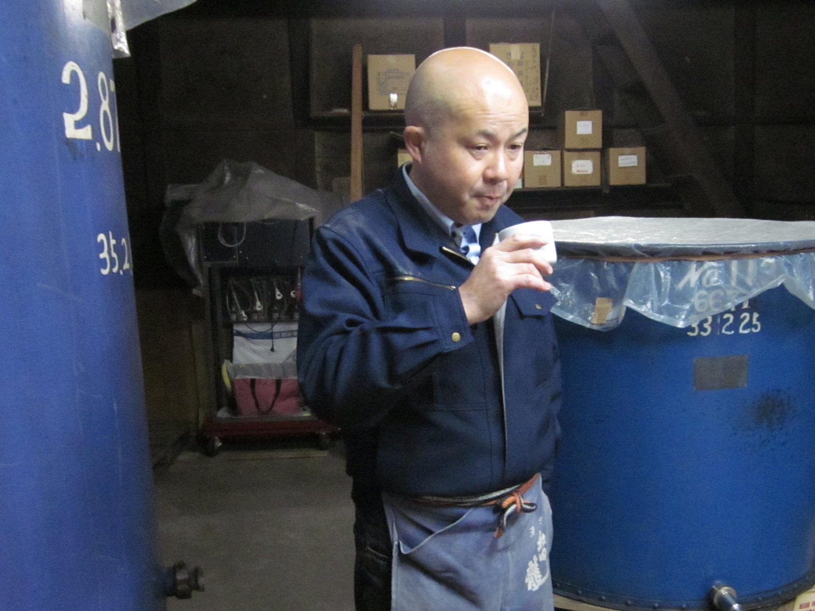 仕込みタンクの前で酒の出来を利く蔵元